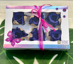 The image shows a box of 6 royal blue and gold rosebuds. The box is decorated with a pink butterfly and flowers. there is also a sticker saying "Home is where your mom is". 