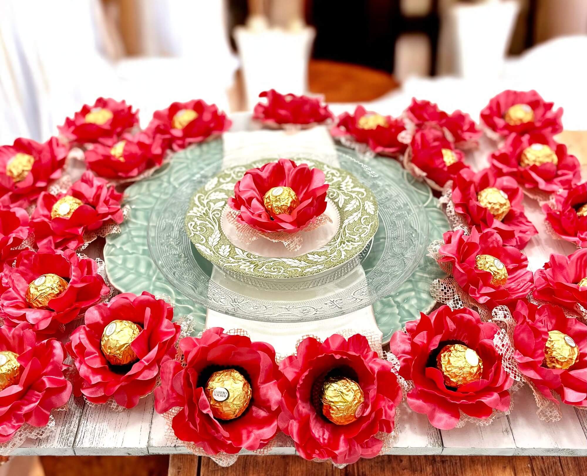 Decorative table setting with coral color flowers and gold candies on a white plate.