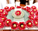 Decorative table setting with coral color flowers and gold candies on a white plate.