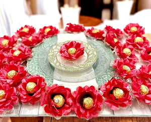 Decorative table setting with coral color flowers and gold candies on a white plate.