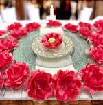 coral flower-shaped containers with gold chocolates on a wooden surface.