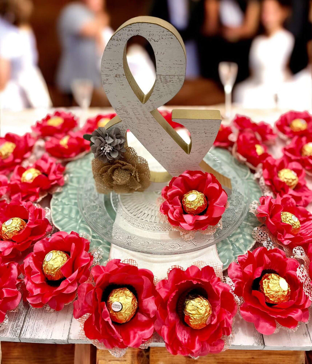 Decorative centerpiece with coral flowers and gold candies on a table.