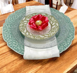 Decorative table setting with a coral flower and gold center on a green plate.