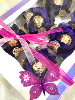 Ferrero Rocher chocolates in a decorative box with  royal blue flowers and pink ribbon.