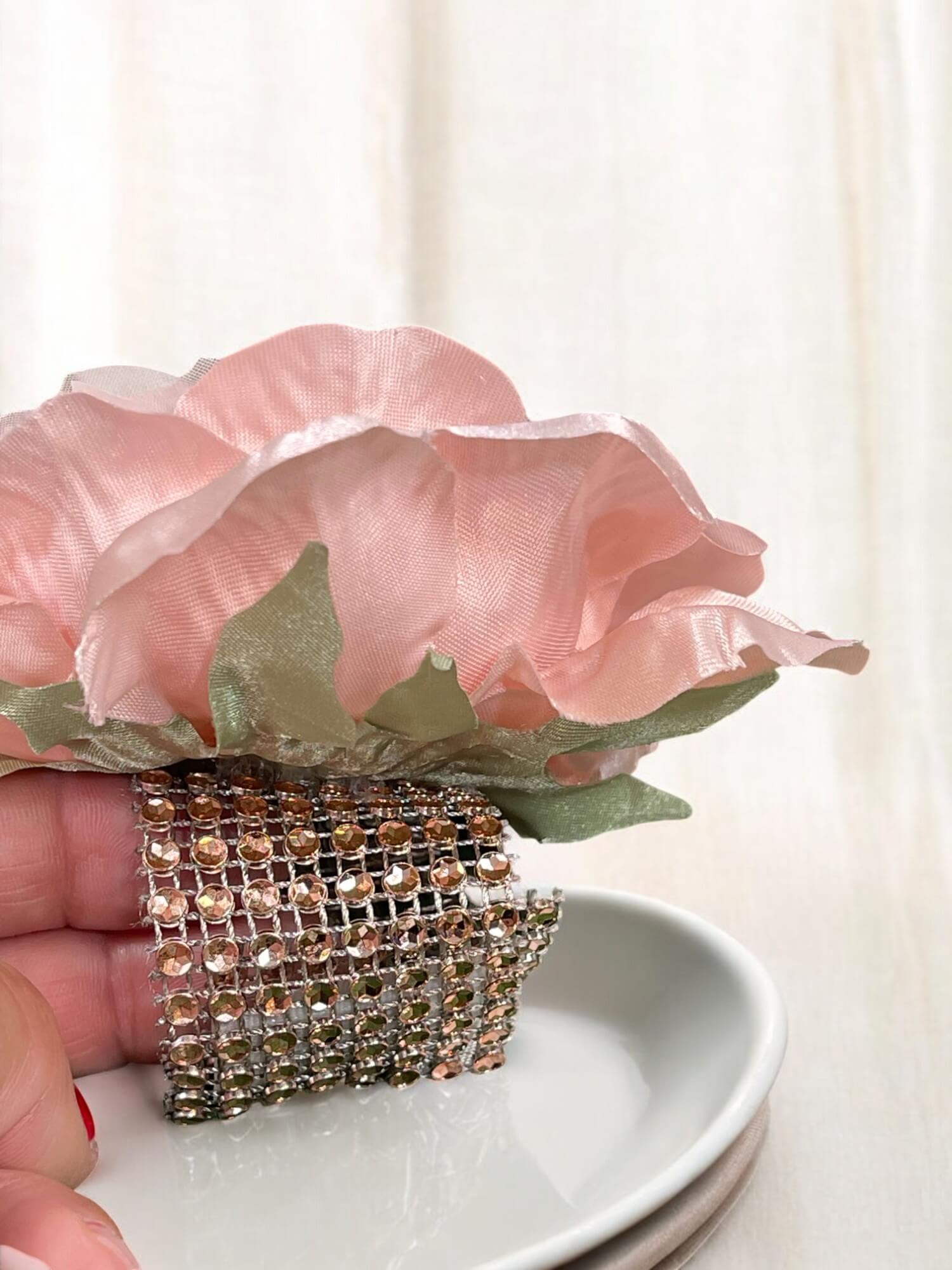 Decorative napkin ring with pink flower and rhinestones on a white surface