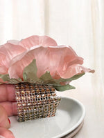 Decorative napkin ring with pink flower and rhinestones on a white surface