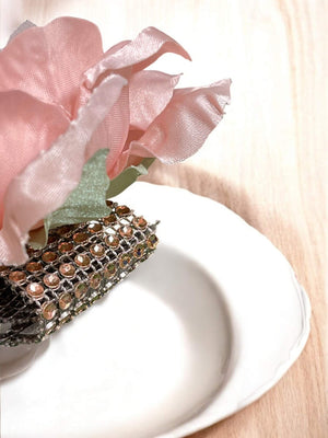 Decorative napkin with pink flowers and a textured border on a white plate.