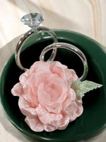 Pink rose napkin ring on a green dish