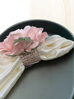 Decorative napkin ring with pink flower and rhinestones on a black plate.