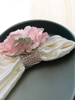 Decorative napkin ring with pink flower and rhinestones on a black plate.