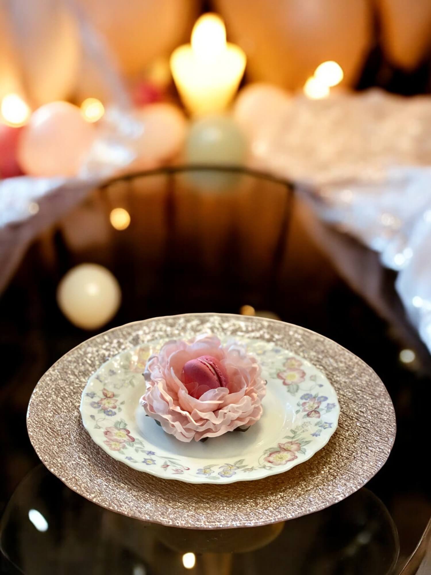 Decorative plate with a pink flower holding a macaroon on a blurred background