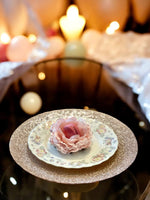 Decorative plate with a pink flower holding a macaroon on a blurred background