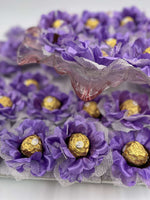 Ferrero Rocher chocolates in purple flower-shaped boxes on a white background