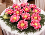Decorative arrangement of pink flowers with gold centers on a white tablecloth.