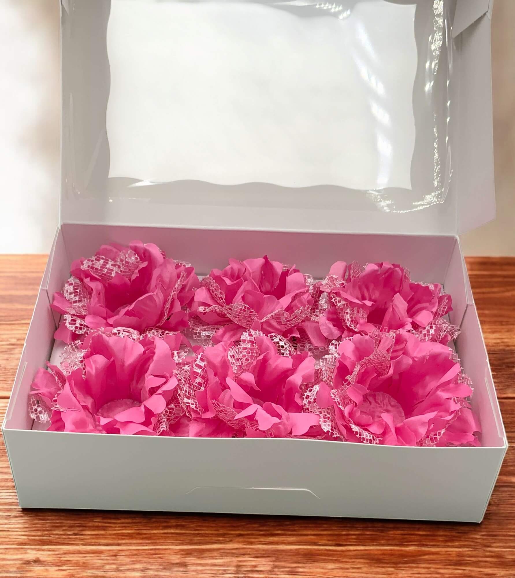 Pink garters with lace details in a white box on a wooden surface