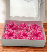 Pink garters with lace details in a white box on a wooden surface