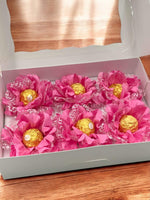 Ferrero Rocher chocolates arranged in a decorative manner with pink flowers in a white box.