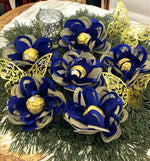 Centerpieces with royal blue and gold flowers sitting on greenery.
