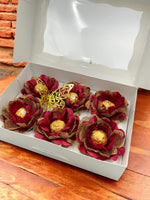 Decorative flowers with gold centers in a white box on a wooden surface