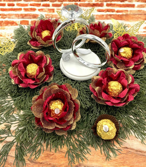 Decorative ring stands with red floral designs and chocolate eggs on a wooden surface.