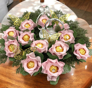Decorative arrangement of pink roses with gold chocolate encase in each flower on a wooden surface