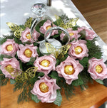 Bouquet of pink flowers with gold chocolate eggs and butterfly decorations on a wooden table.