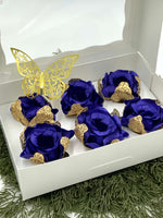 Decorative set of blue roses with gold accents and a butterfly on a white box.