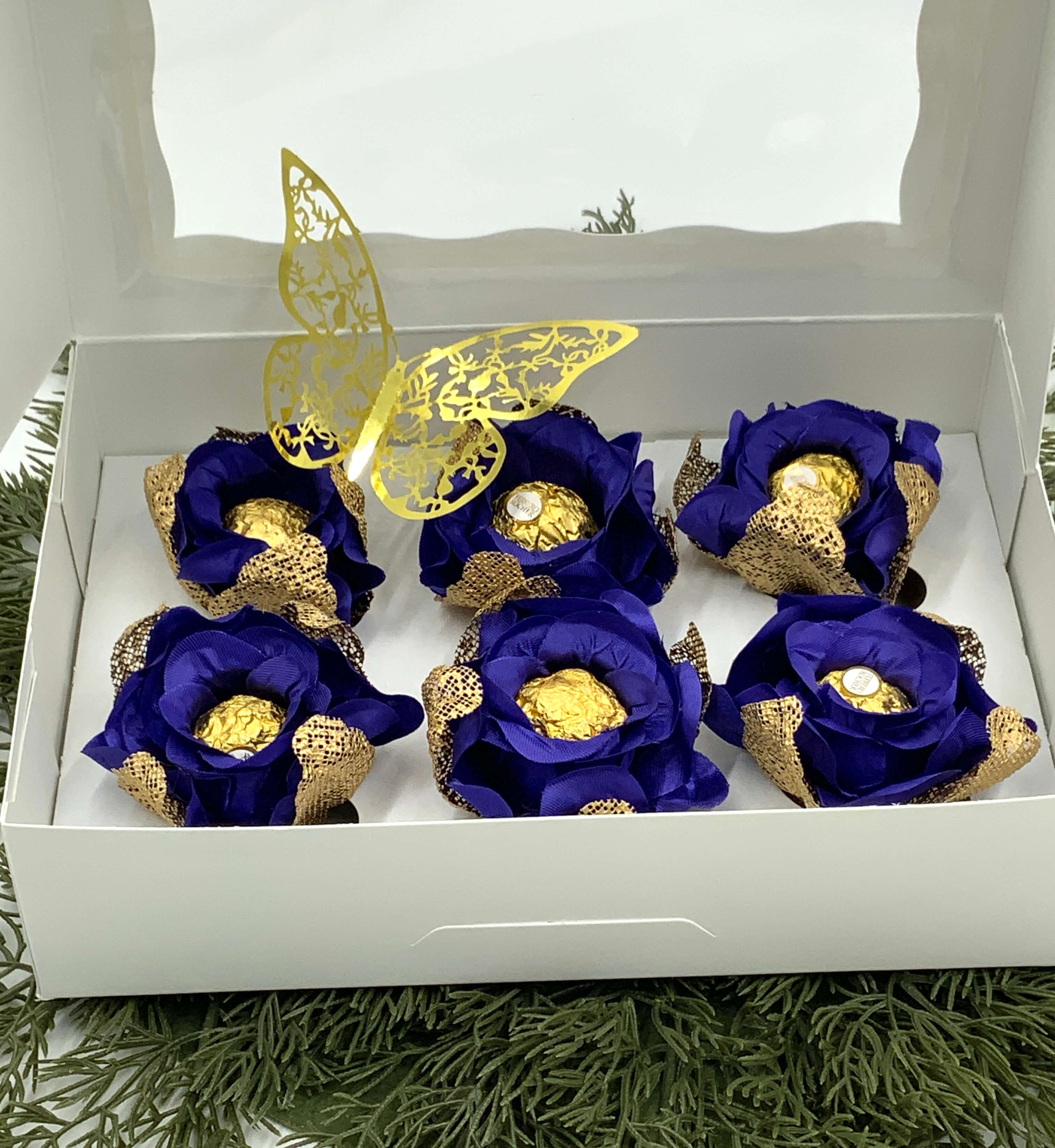 Decorative royal blue and gold flowers in a white box with a butterfly design on a green textured background.