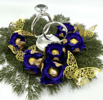 Decorative wreath with blue flowers, gold accents, and silver rings on a white background