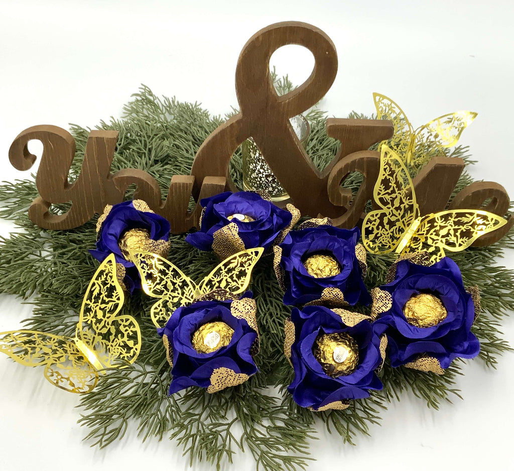 Decorative arrangement with blue flowers, gold butterflies, and wooden letters on a white background