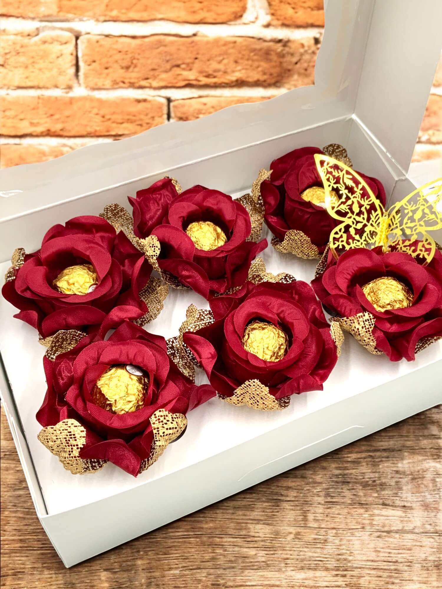 Red flowers with gold centers in a white box against a brick wall background