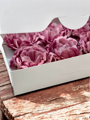 rose gold flowers in a white box on a wooden surface