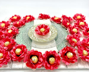 A centerpiece made of  artificial coral color silk flowers with gold round chocolate, designed for use as party favors or decorations.