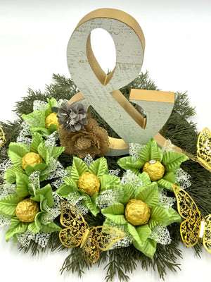 green flowers centerpiece holding a chocolate truffle. There is a sign & and gold butterflies to complete the centerpiece
