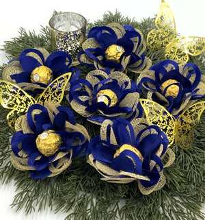 Centerpieces with royal blue and gold flowers sitting on greenery.