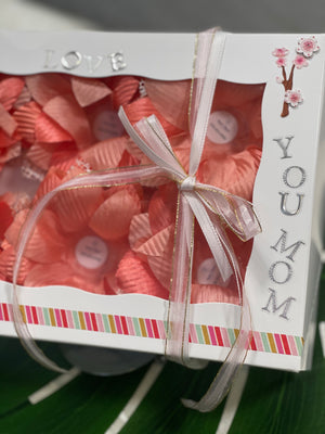 White box decorated with letter saying "Love You Mom". There are 6 coral color flowers in it.