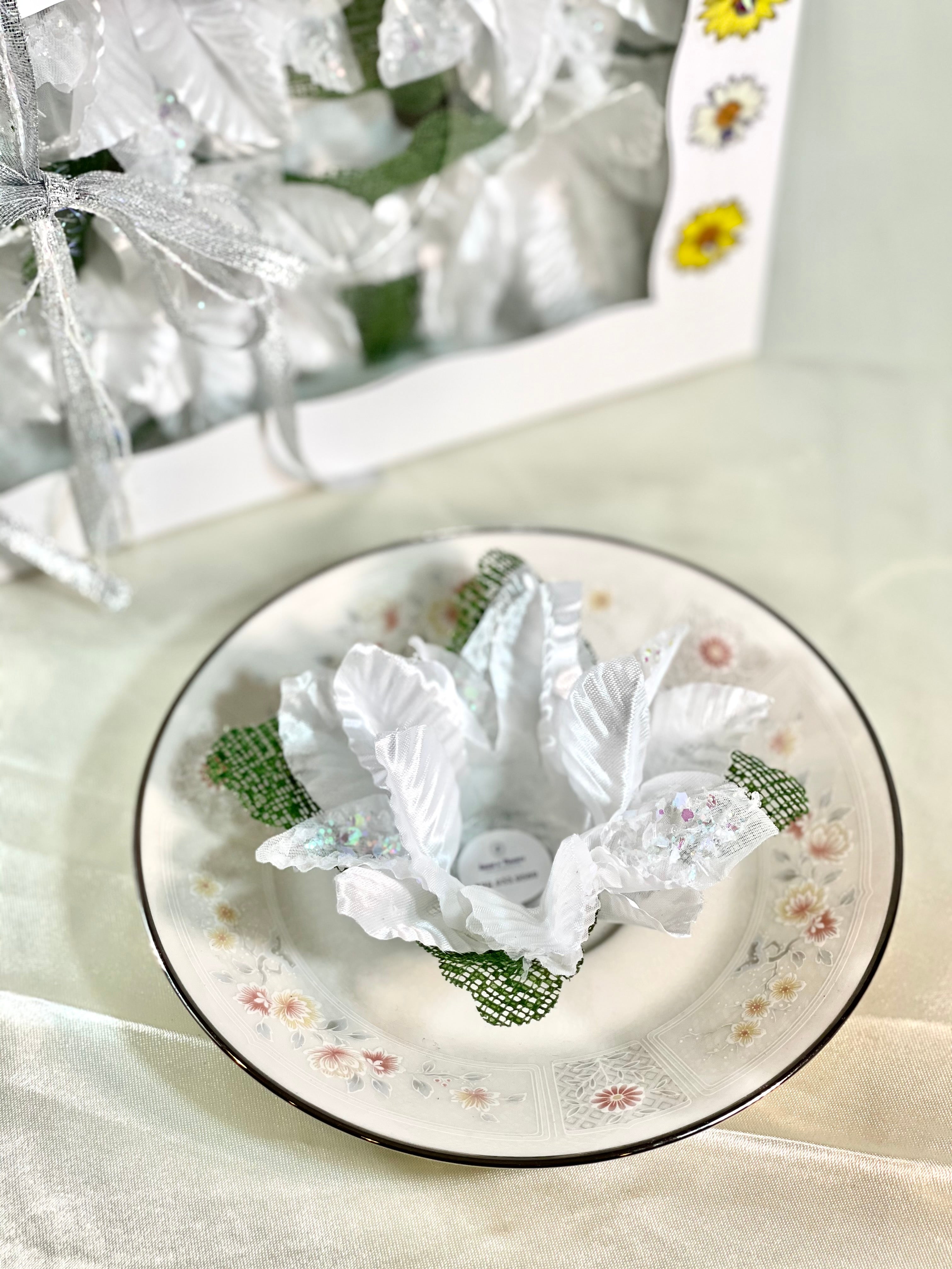 white flower with green accent sitting on a porcelain saucer