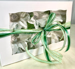 Image of a white box with green ribbon. The box comes with 6 flowers. These flowers are white with green accents. Each flower has a little cup in the middle which is used to hold sweets. Theses flowers are sweet holders.